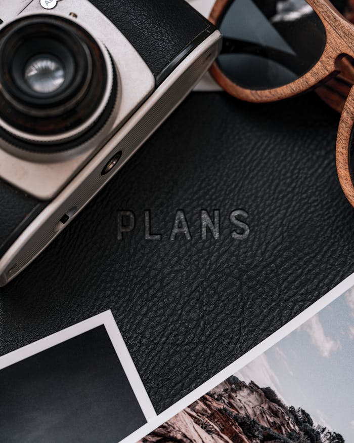 Close-up of a vintage camera and travel planning journal with printed photos.